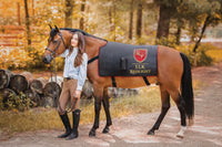 Elk Redlight horse red light therapy blanket worn by bay horse with rider in autumn forest – equine photobiomodulation back and topline recovery